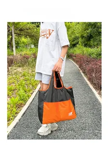 Detail of the black and orange waterproof nylon travel tote bag with branded logo