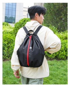 Detail of black foldable backpack featuring a distinctive red center zipper and mountain logo