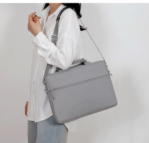 Detail view of gray laptop bag with fabric texture and adjustable shoulder strap on model