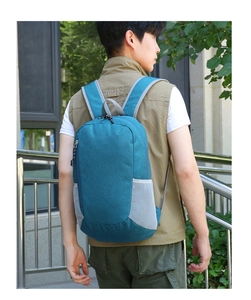 Détail d'un sac à dos pliable bleu paon avec des poches latérales en filet sur modèle