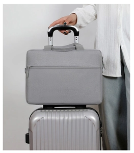 Detail of light gray laptop bag with back strap attached to a silver suitcase handle