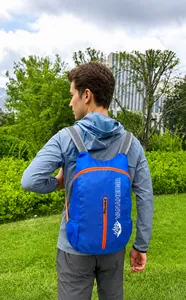 Blauwe opvouwbare rugzak met oranje ritsen getoond tijdens gebruik buiten