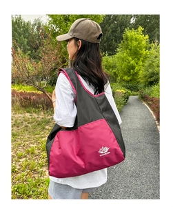 Outdoor shot of a foldable pink and black nylon travel tote bag with VANAHEIMR logo