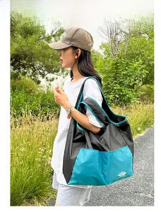 Outdoor shot of a black and blue large capacity folding travel bag worn on the shoulder