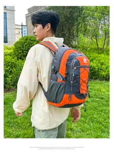 Outdoor hiking backpack in orange and grey showing side view on male model in a park