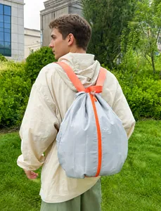 Detailansicht faltbarer grauer Rucksack mit orangen Reißverschlüssen und leichtem Stoff