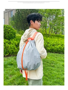 Detail view of foldable grey backpack with orange straps on female model outdoors
