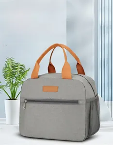 Close-up of grey insulated lunch bag with orange handles and functional storage pockets