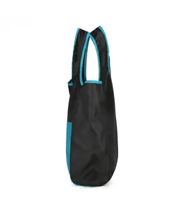 Detail of a foldable travel bag with black nylon fabric and vibrant blue trim accents