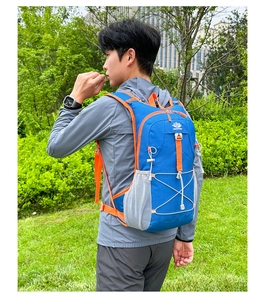 Detailansicht eines blau-orangen Outdoor-Rucksacks, getragen von einem Modell im Freien