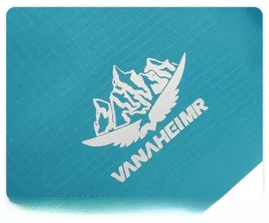 Detailed close-up of white mountain logo printed on lake blue textile travel bag