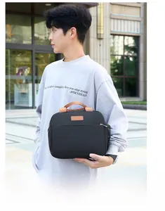 Man carrying a black insulated lunch bag with brown handles in a modern urban setting