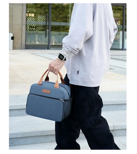 Outdoor shot showing denim blue waterproof lunch bag with brown straps and side mesh pocket