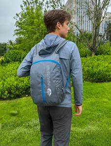 Grijze opvouwbare outdoor rugzak met blauwe waterdichte rits en netvak getoond op een model