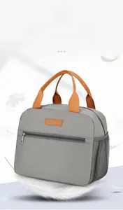 Detail view of lightweight grey oxford fabric lunch bag with orange handles and side mesh pocket