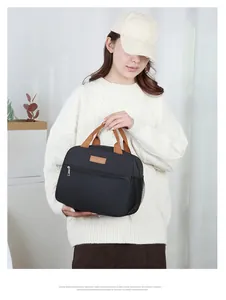 Detail view of black oxford lunch bag with brown handles and side mesh pocket in daily use