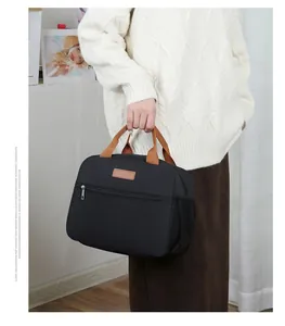 Detail of black thermal lunch bag with brown handles and side mesh storage pocket