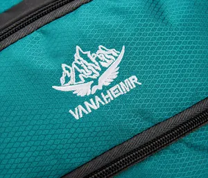 Macro view of the turquoise ripstop fabric and detailed logo embroidery on the backpack