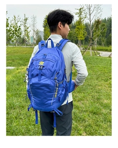 Side view of dark blue hiking backpack with ergonomic straps on model in outdoor setting
