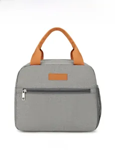 Macro detail of insulated lunch bag showing front zipper pocket and orange handles