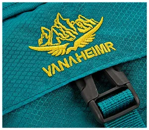 Detail of teal outdoor backpack featuring ripstop fabric and yellow brand embroidery