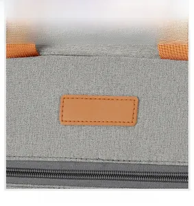 Detail of gray oxford fabric lunch bag with orange handle and leather patch