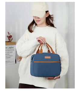 Bolsa térmica azul con asas marrones y bolsillo de malla sostenida por una persona