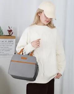 Detail of grey insulated lunch bag with orange-brown handles and side mesh pocket