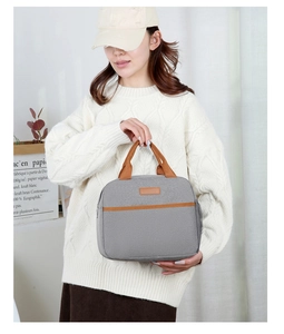 Vista detallada de la bolsa térmica gris con bolsillo de malla y elegante detalle de cuero