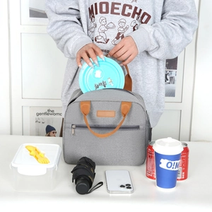 Grey insulated Oxford cloth lunch bag with brown leather handles and front zipper pocket