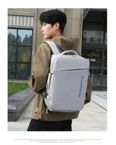 Vista lateral de mochila de negocios gris expandible con hebillas en modelo masculino