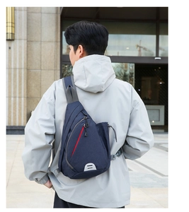 Detail of navy blue crossbody chest bag with red zipper and gray reflective safety patch