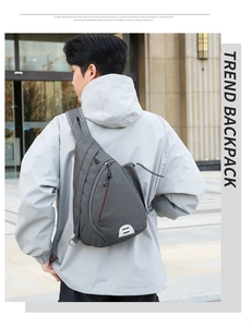 Detail of grey oxford cloth chest bag with red zipper accents and D-ring buckle