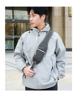 Detail view of the gray oxford chest bag showing the headphone port and reflective safety strip