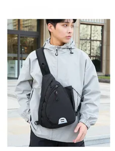 Outdoor shot of a black nylon sling bag with triangular structure and reflective detail