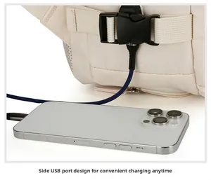 Dettaglio della porta di ricarica USB laterale su uno zaino da viaggio beige con smartphone