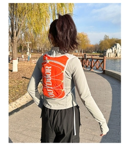 Detail of lightweight orange running vest backpack with reflective OUTDOOR print and drawstring