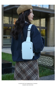 Outdoor street style view of a light blue minimalist crossbody bag with nylon strap