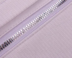 Primer plano de la tela lavanda y la cremallera de metal plateado de la bandolera