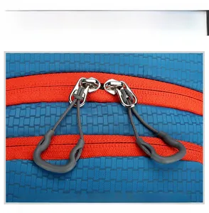 Detail of blue outdoor backpack featuring dual silver metal zippers with gray anti-slip pullers