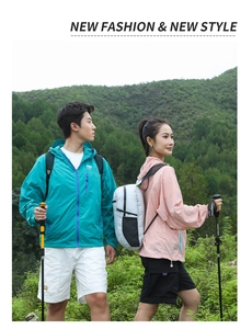 Couple wearing lightweight blue and pink outdoor hiking windbreakers with folding backpacks