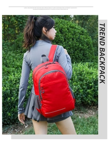 Detail of red foldable sports backpack showing side mesh pocket and safety reflective strip