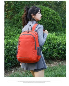 Outdoor lightweight orange backpack with reflective safety strip shown on a model