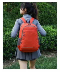 Detail view of bright orange lightweight outdoor backpack with a white reflective safety strip