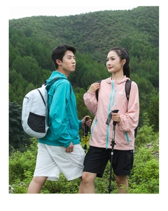Outdoor couple wearing hiking jackets and grey backpacks exploring a mountain trail