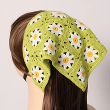 Detail eines handgehäkelten grünen Bandanas mit weißen Gänseblümchen und Strickstruktur