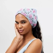 Nahaufnahme eines blau gestrickten Bandanas mit rosa Blumenmuster an einem Modell