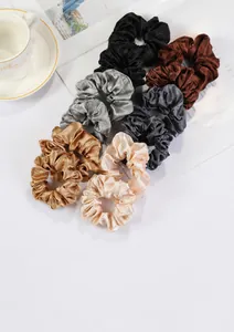 Macro detail of assorted satin velvet scrunchies in various neutral colors for hair styling