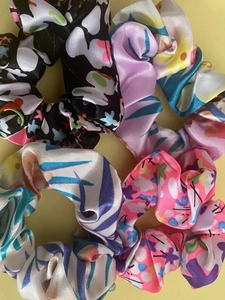 Detail shot of assorted floral satin scrunchies with smooth silky texture and vivid prints