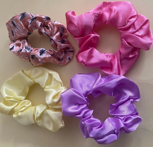 Detail view of 4-pack satin scrunchies in bright pink, yellow, purple, and leaf patterns